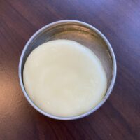 A bar of hand lotion lays in a metal tin.