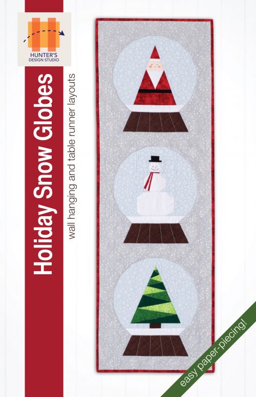 Holiday Snow Globes is a foundation paper piecing pattern that features three snow globes. One has a triangle shaped santa, the second has a snowman with a red scarf, and the third has an evergreen tree made from several green fabrics.
