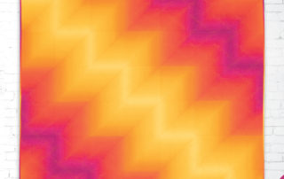 Ombré waterfall is a quilt made with ombre fabric sewn together in half square triangles that make color zig zag across the top of the quilt.