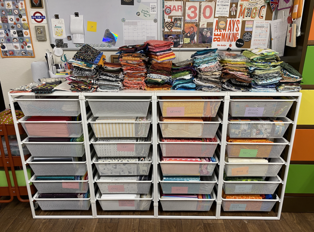 Neatly organized white wire Ikea drawers holding a fabric stash. Downsized fabrics are on top of the drawers, ready for a destash.