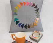 Turning Points features paper piecing and prairie points to make a three dimensional flying geese in a circular formation.